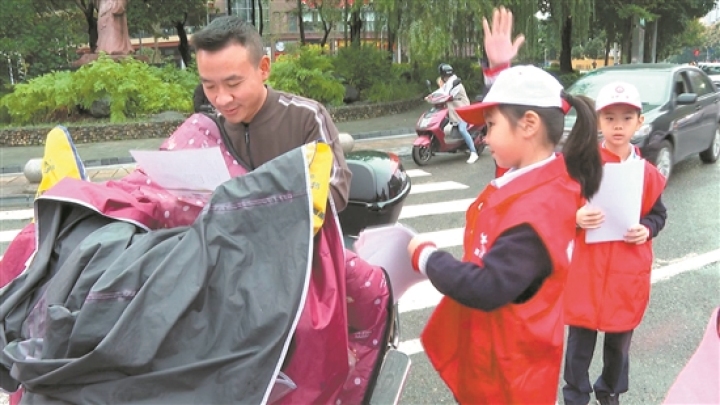 小小志愿者為過往行人和車輛發放文明出行宣傳單。.jpg