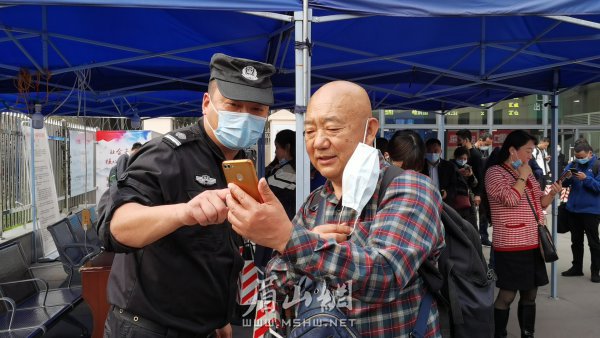 眉山東站出站口，工作人員教老人掃健康碼。
